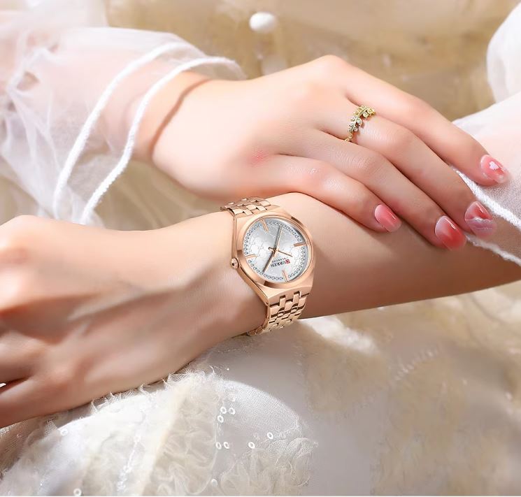 Rose gold watch on a wrist with a soft, blurred background