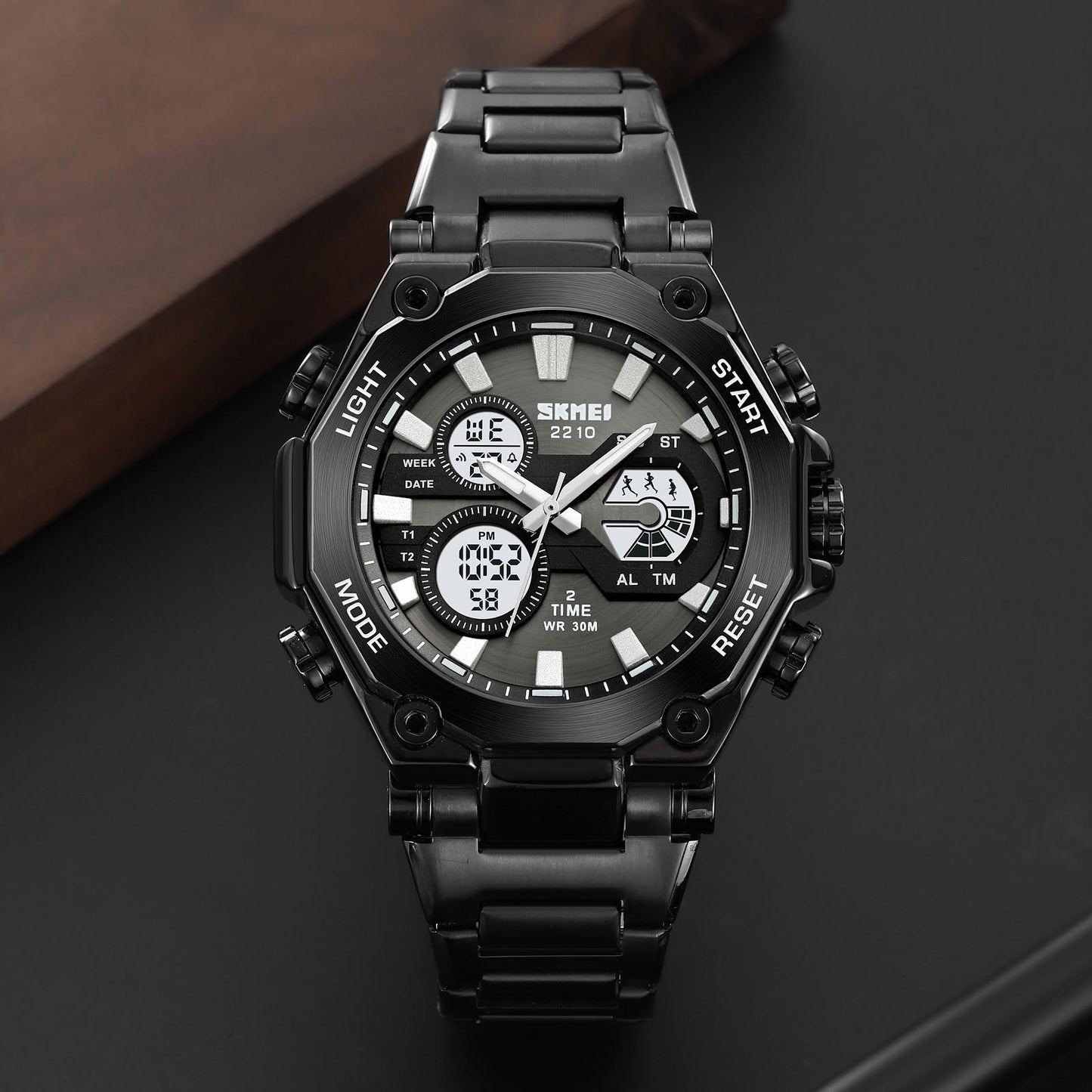 Black digital wristwatch with metal strap on a dark background