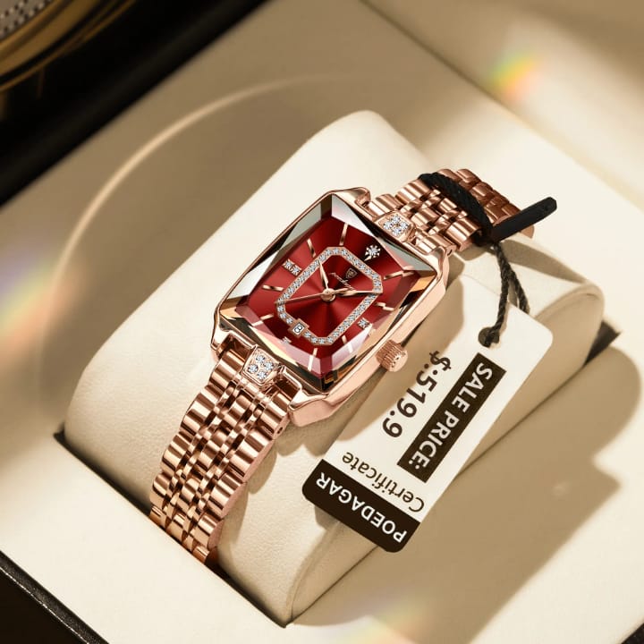 Luxury watch with red face and rose gold band in a box, brand label visible