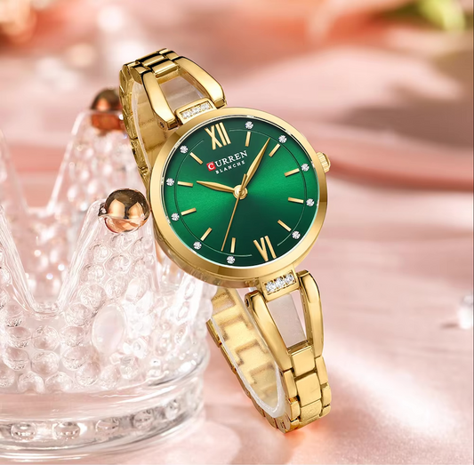 Gold wristwatch with a green dial on a blurred background