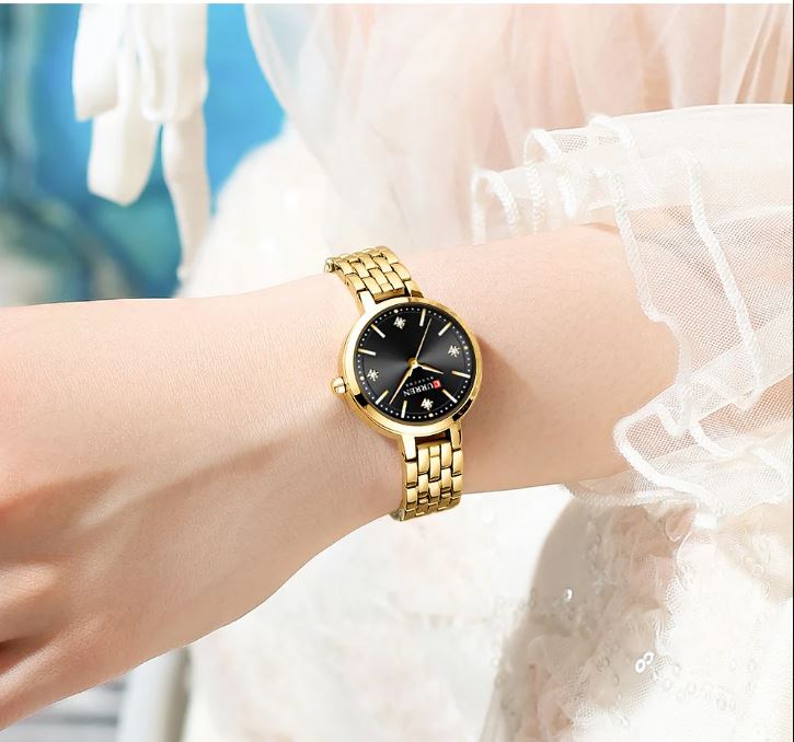 Gold wristwatch on a wrist with a blurred background