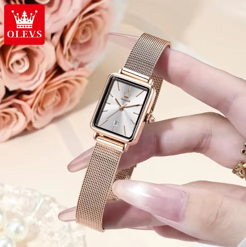 Rose gold watch held by a hand with pink roses in the background, featuring the OLEVS brand.