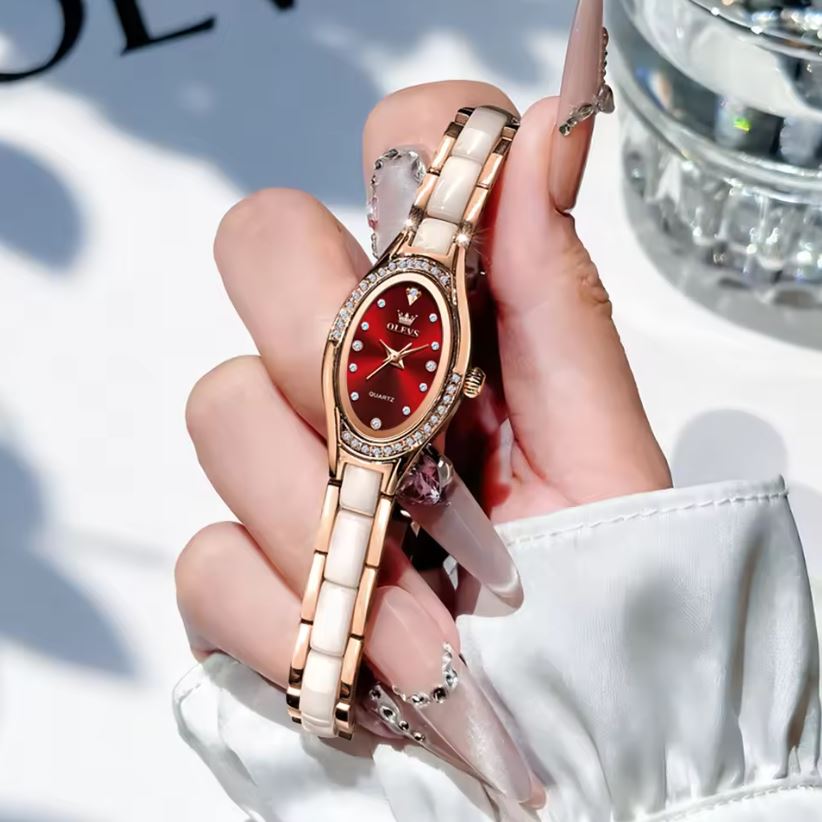 Hand holding a rose gold watch with a red face