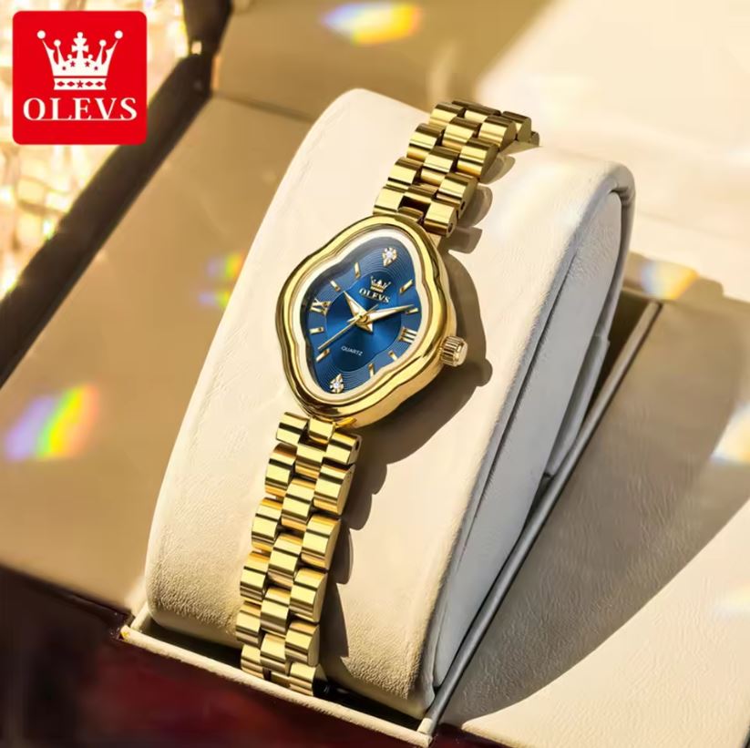 Gold wristwatch with blue face on a white cushion, brand 'OLEVS' visible