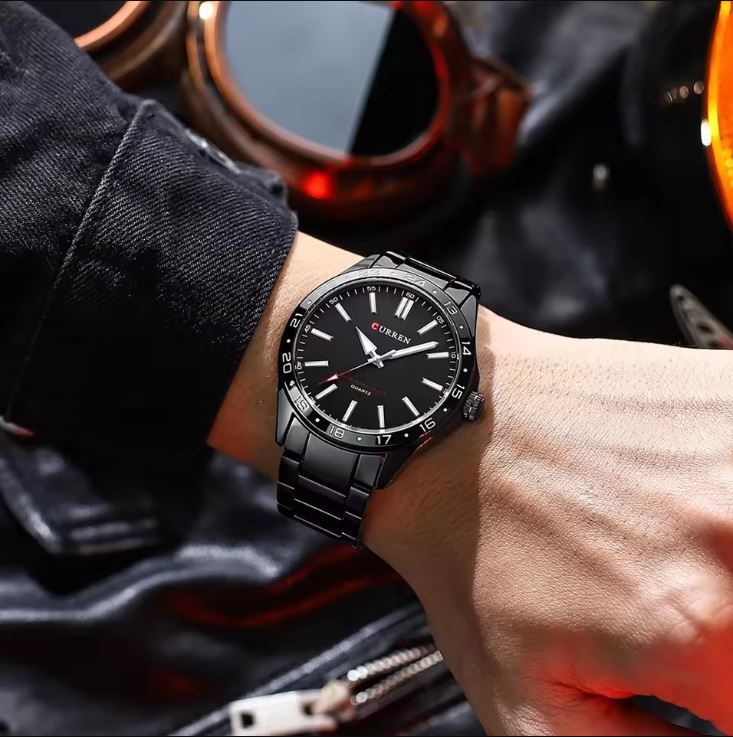 Black wristwatch on a person's wrist with a blurred background