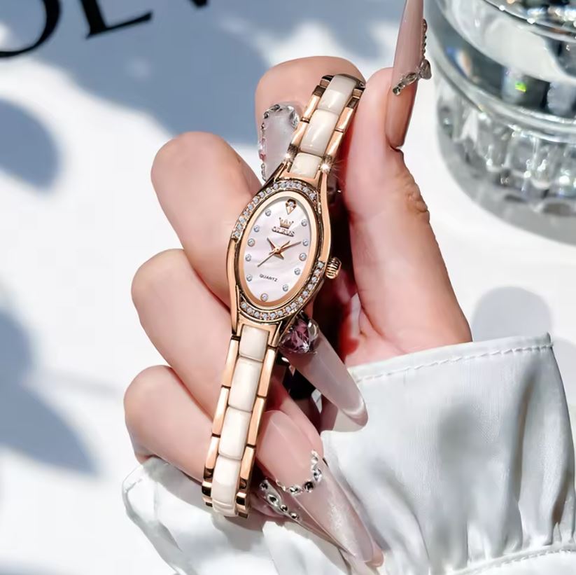 Rose gold watch with white face held in a hand against a blurred background