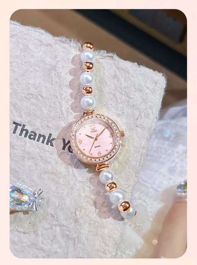 Rose gold watch with pearl strap on a textured surface