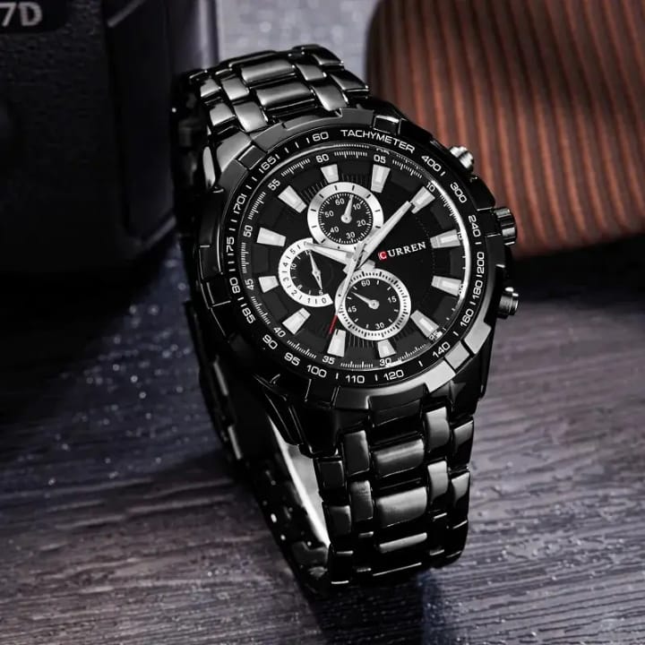 Black wristwatch with metal strap on a dark surface