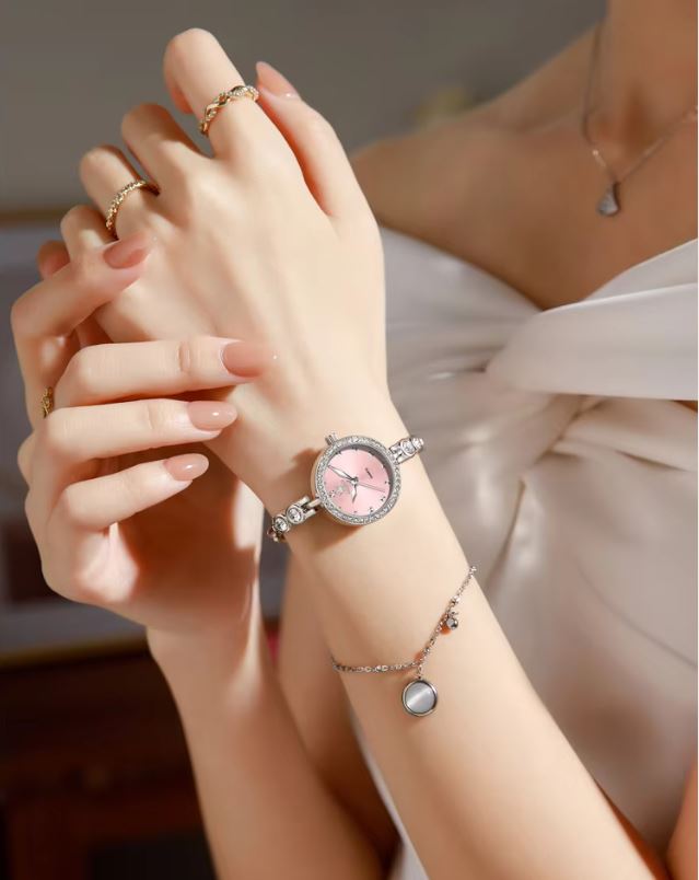 Close-up of a person's wrist wearing a pink watch with a blurred background