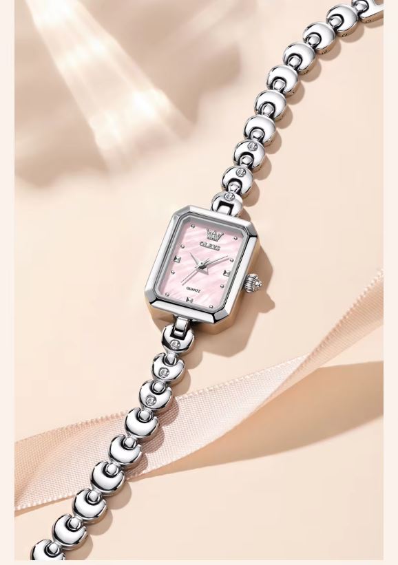 Silver watch with a pink face on a beige fabric background