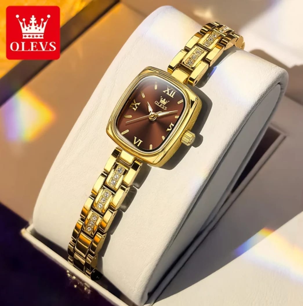 Gold wristwatch with brown face on a white cushion, brand 'OLEVS' visible