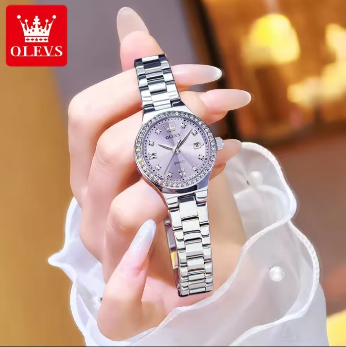 Silver watch held by a hand with a blurred background and OLEVS logo.