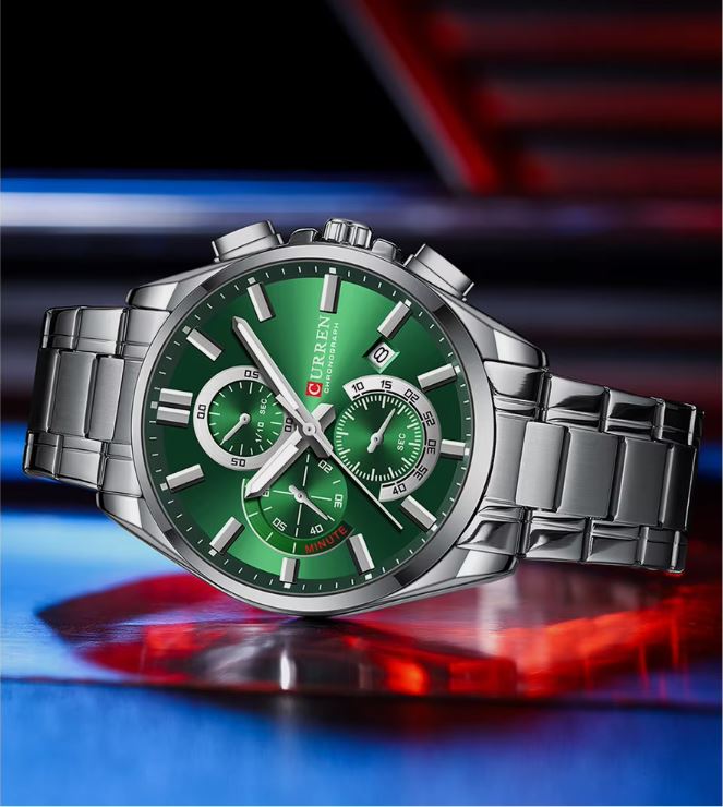 Silver watch with a green face on a colorful background