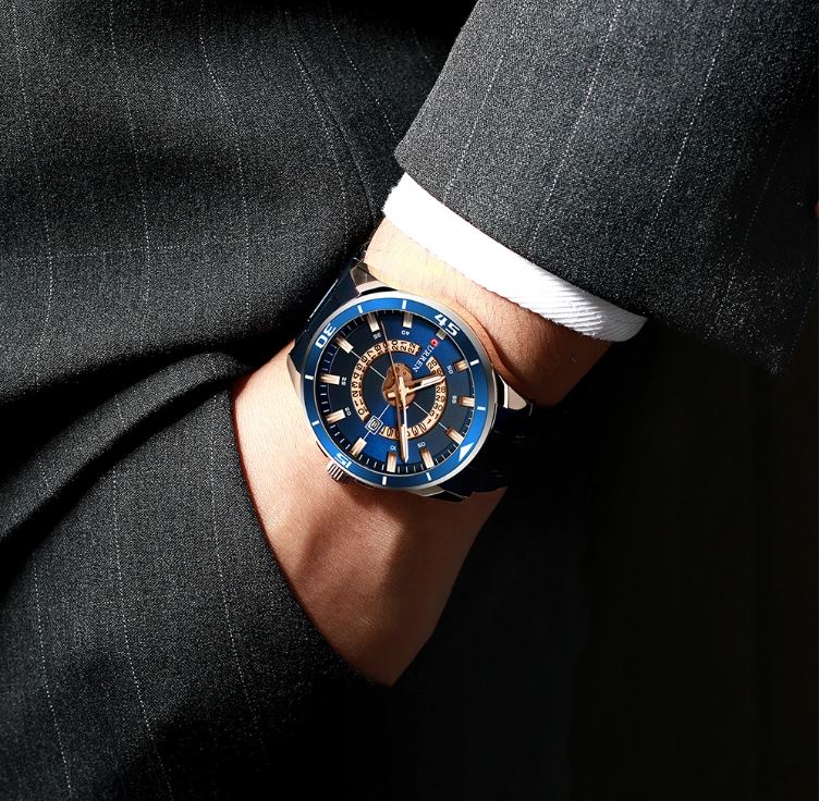 Luxury watch with blue dial on a person wearing a suit
