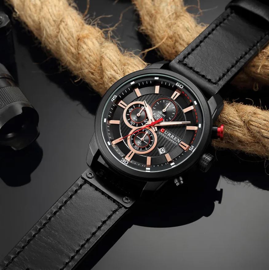 Black wristwatch with detailed face on a dark surface with rope