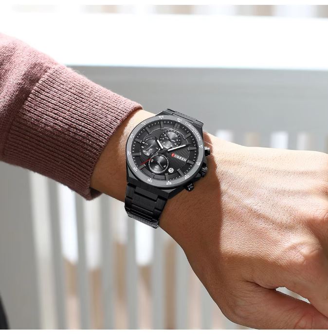 Black wristwatch on a person's wrist with a blurred background