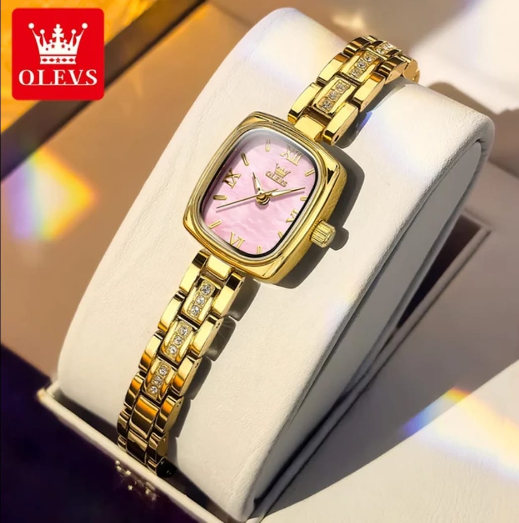 Gold wristwatch with pink face on a white cushion, brand 'OLEVS' visible