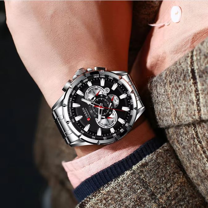Close-up of a person wearing a black and silver watch on a dark background