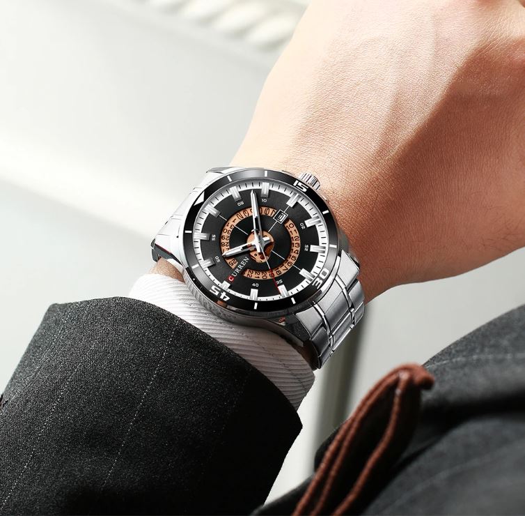 Close-up of a person wearing a silver wristwatch with a black face.