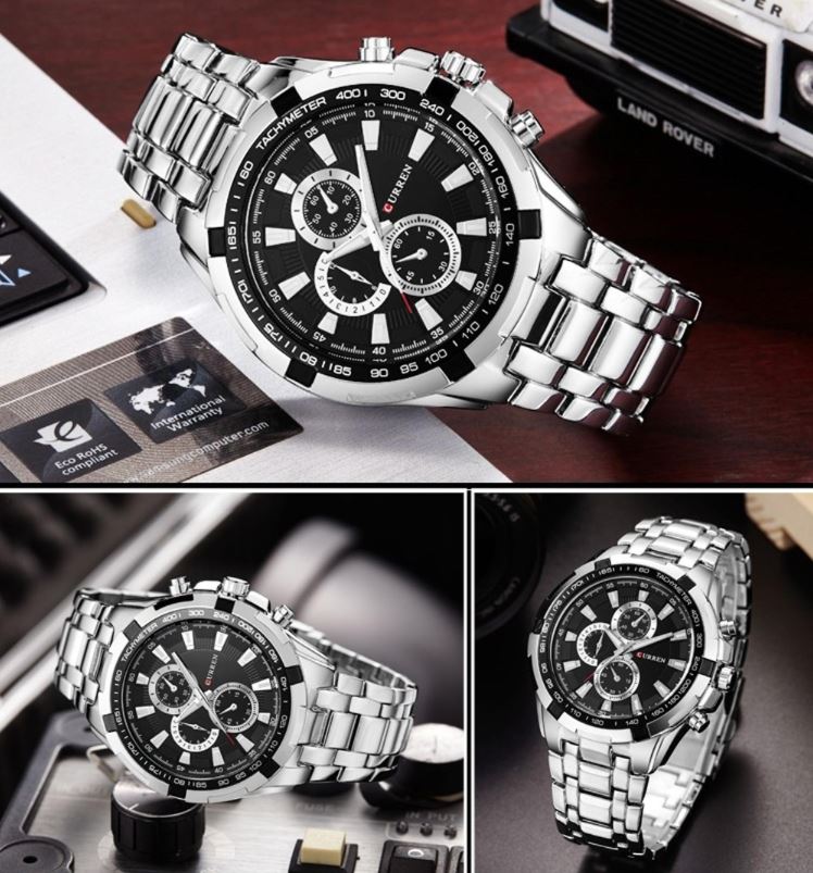 Silver and black watch with metal band on a wooden surface, surrounded by business cards and a Land Rover model.