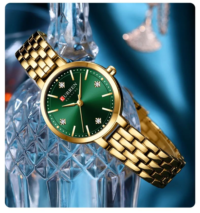 Gold watch with green face on a decorative glass background