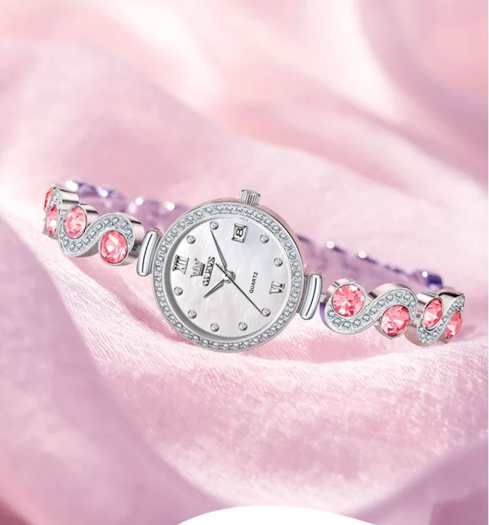 Silver watch with pink gemstones on a pink fabric background