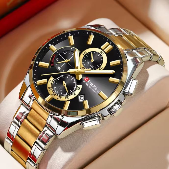 Gold and silver watch with black face on a beige surface