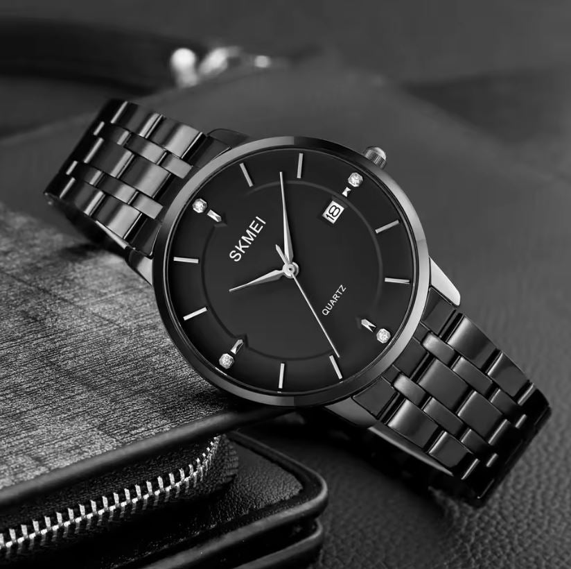 Black wristwatch with metal strap on a textured surface