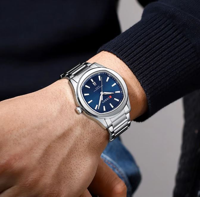 Close-up of a wrist wearing a silver watch with a blue face.