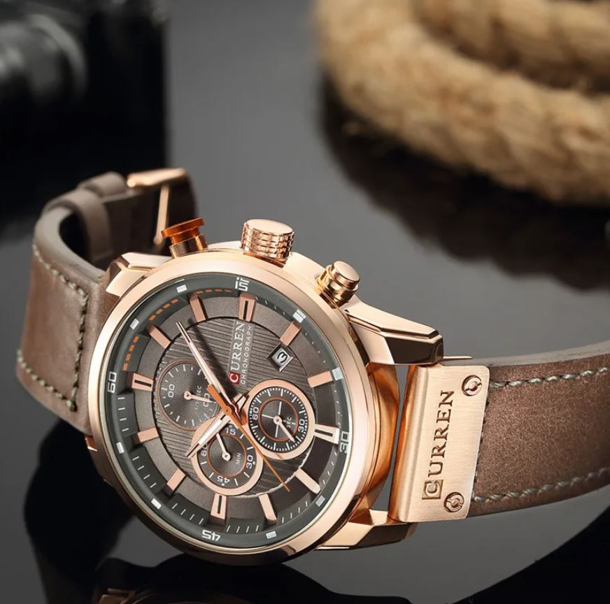 Curren watch with brown leather strap and rose gold accents on a dark background