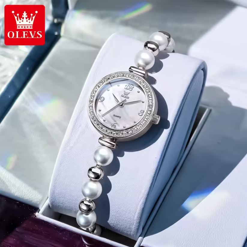 Silver watch with pearl bracelet on a white box, brand 'OLEVS' visible