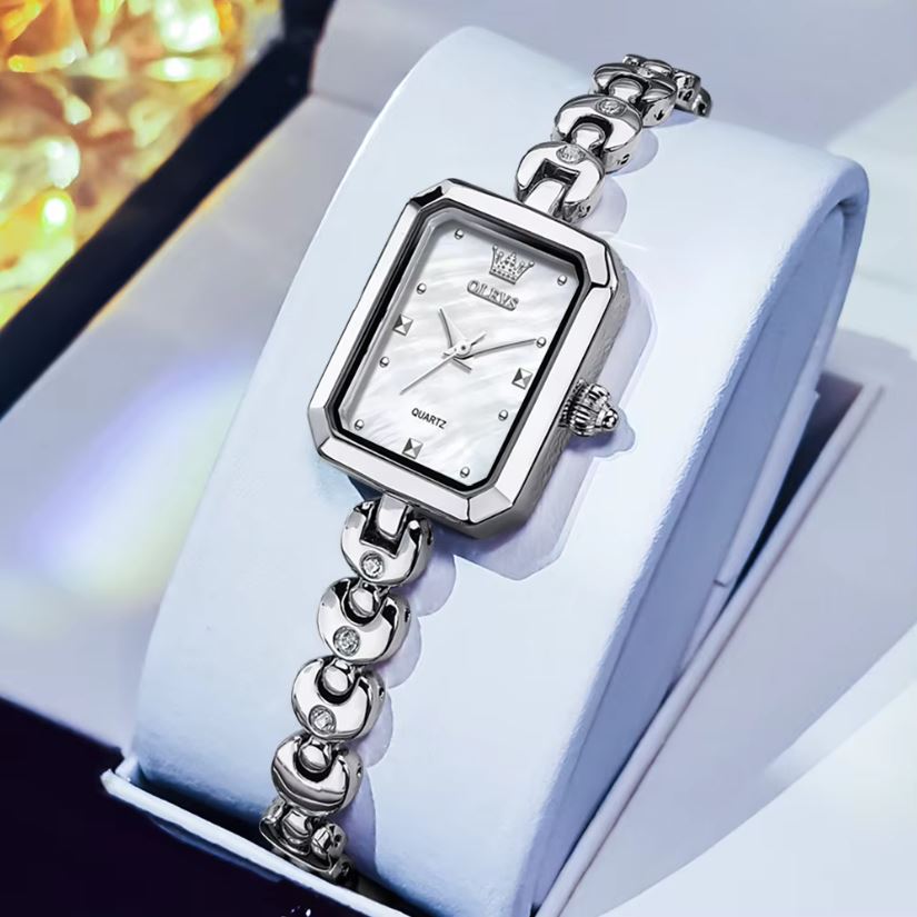 Silver watch with a white face on a light blue background
