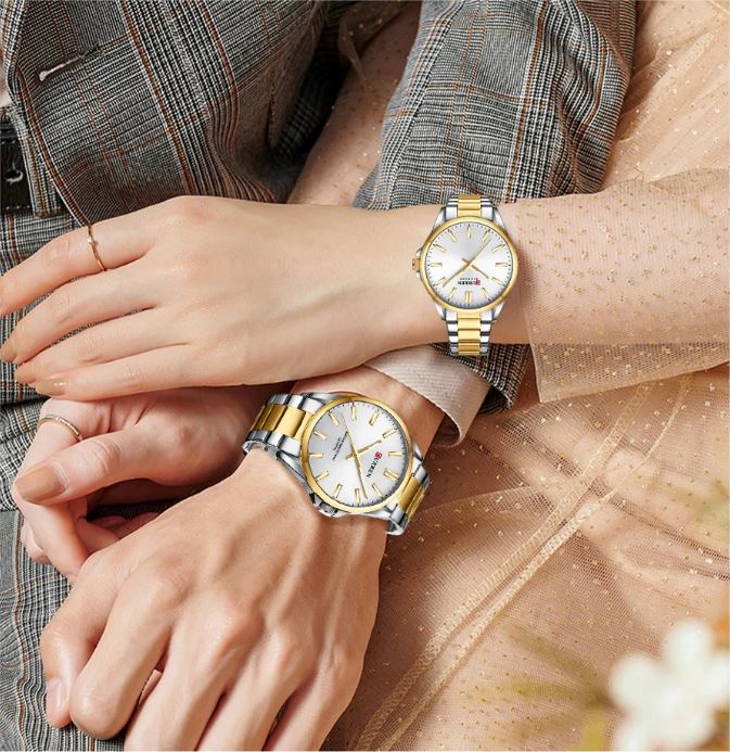 Two wrists wearing gold and silver watches with a blurred background