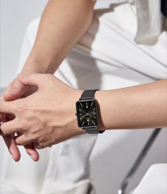 Person wearing a black smartwatch on a plain background