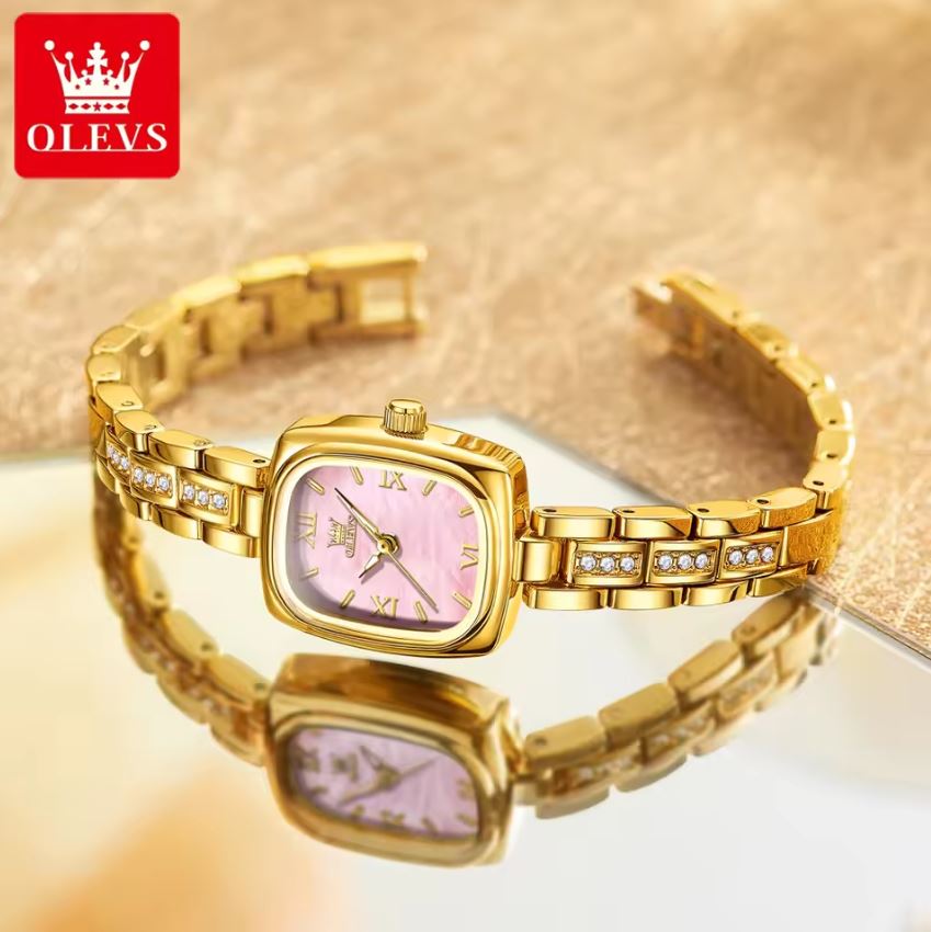 Gold wristwatch with pink face on a reflective surface, OLEVS brand visible.