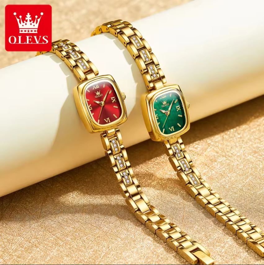 Two gold wristwatches with red and green faces on a beige surface, branded 'OLEVS'.