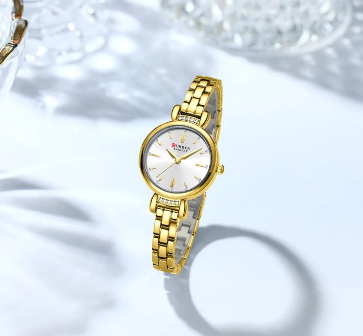 Gold wristwatch with a white face on a light background
