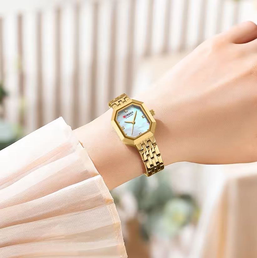 Gold wristwatch on a person's wrist with a blurred background
