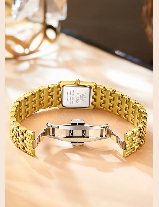 Gold watch with a square face on a beige surface