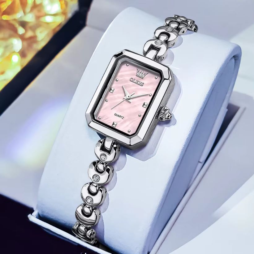 Silver watch with a pink face on a white surface