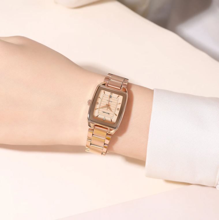 Rose gold watch on a wrist with a white background