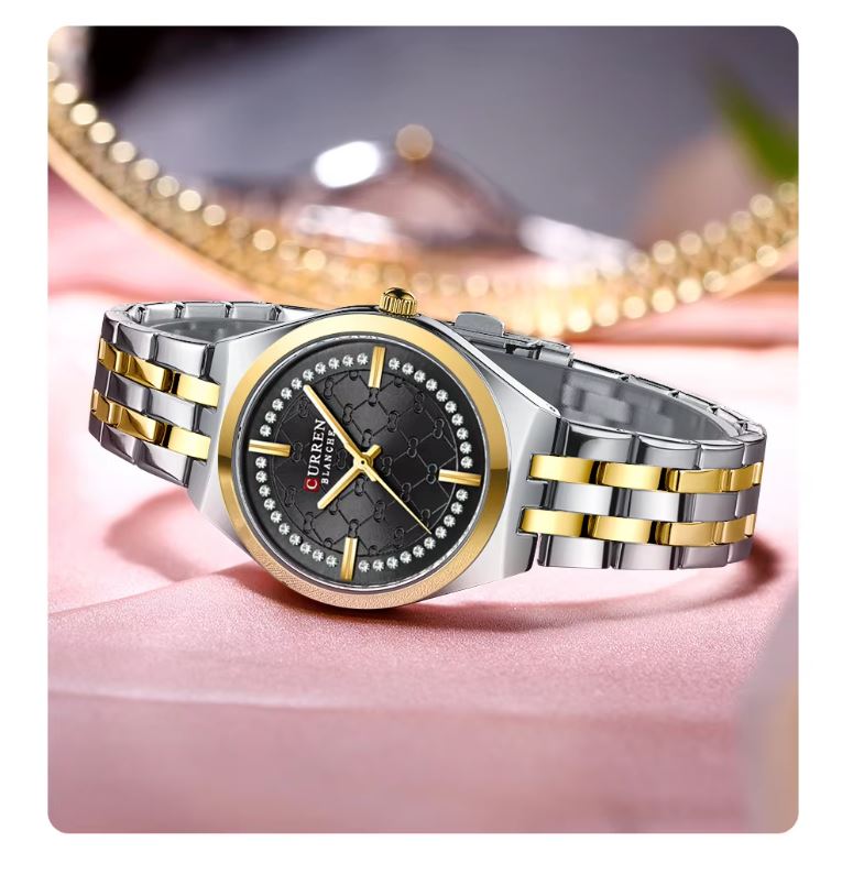 Silver and gold watch with black face on a pink surface