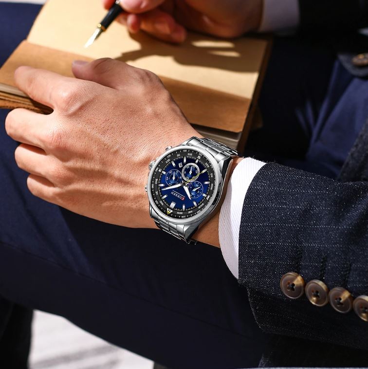 Close-up of a person wearing a watch with a suit and notebook in the background