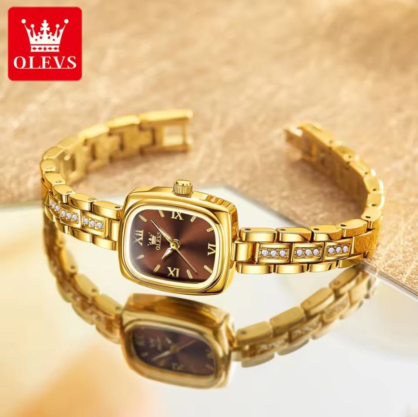 Gold wristwatch with brown face on a reflective surface, OLEVS brand visible.