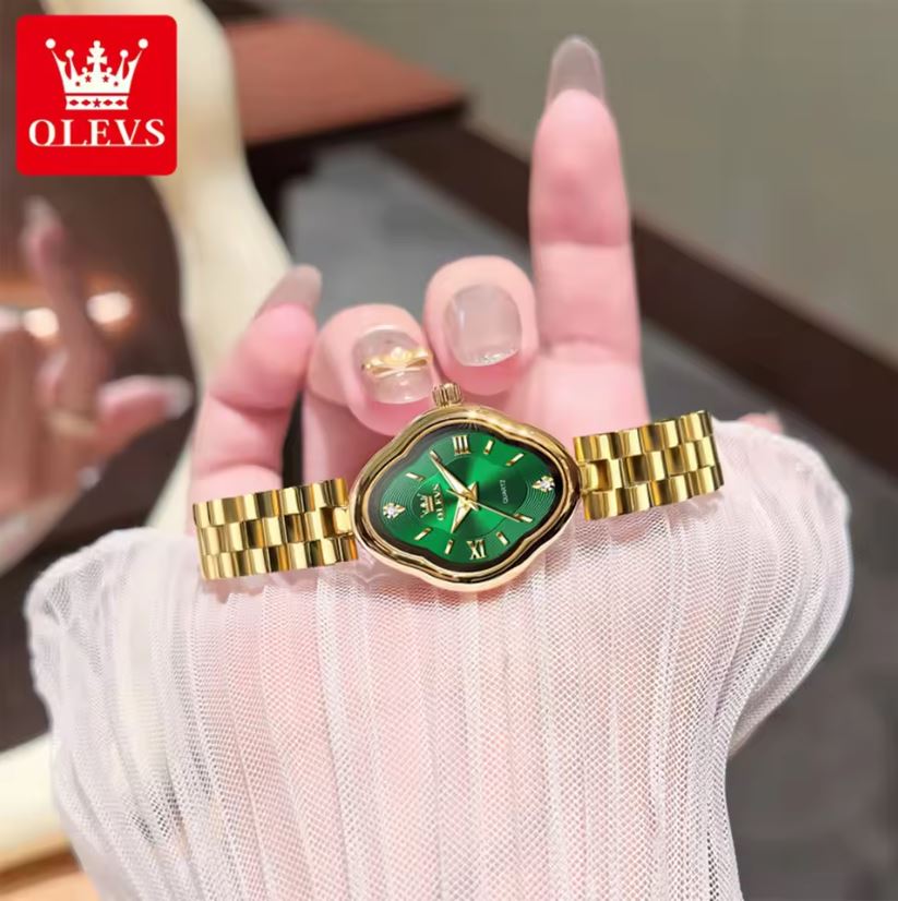 Gold watch with green face held by a hand, OLEVS brand visible
