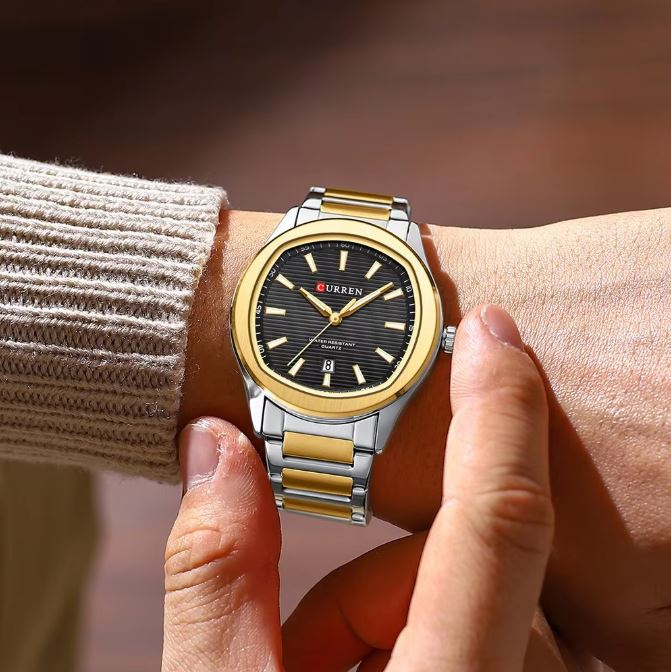 Gold and silver watch on a wrist with a blurred background
