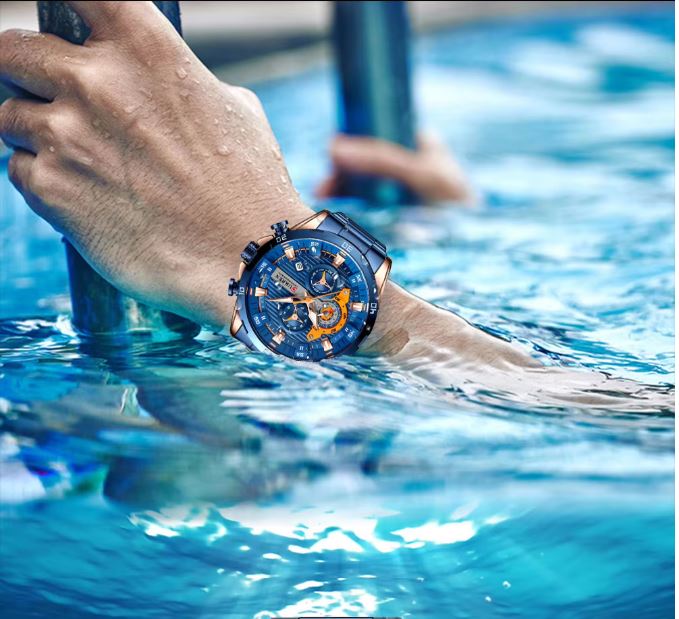 Hand wearing a blue and orange watch underwater
