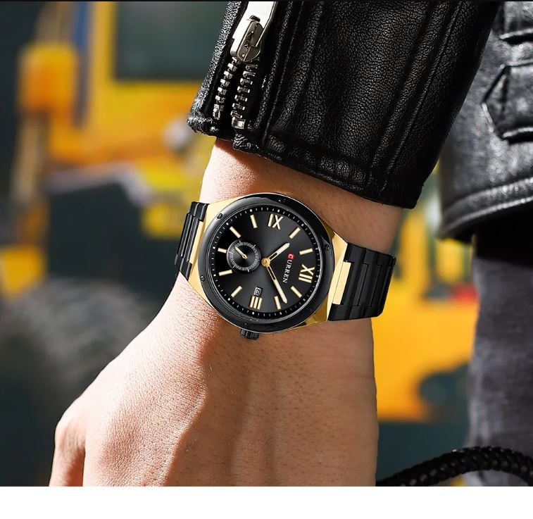 Black and gold watch on a wrist with a blurred background
