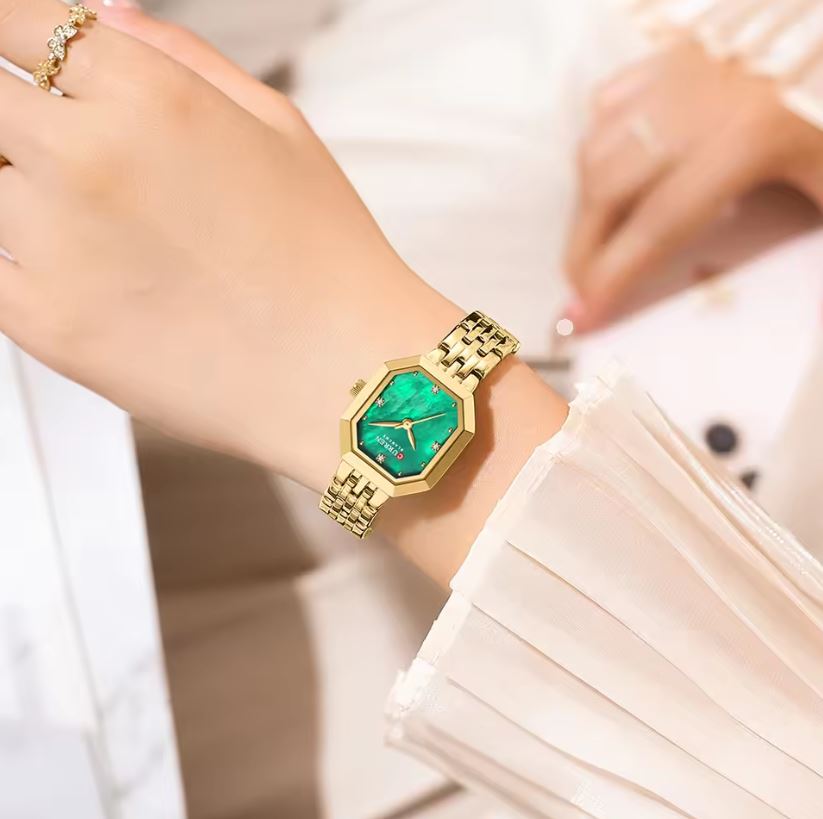 Gold watch with a green face on a wrist, blurred background
