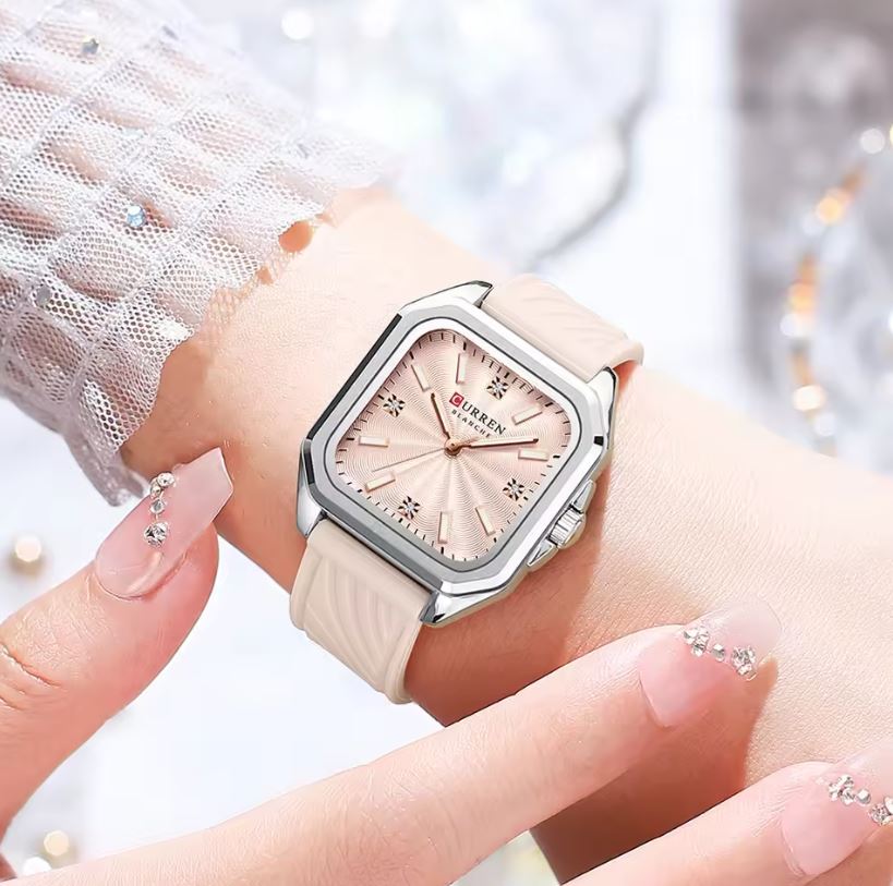 Wristwatch with a pink strap and beige face on a blurred background